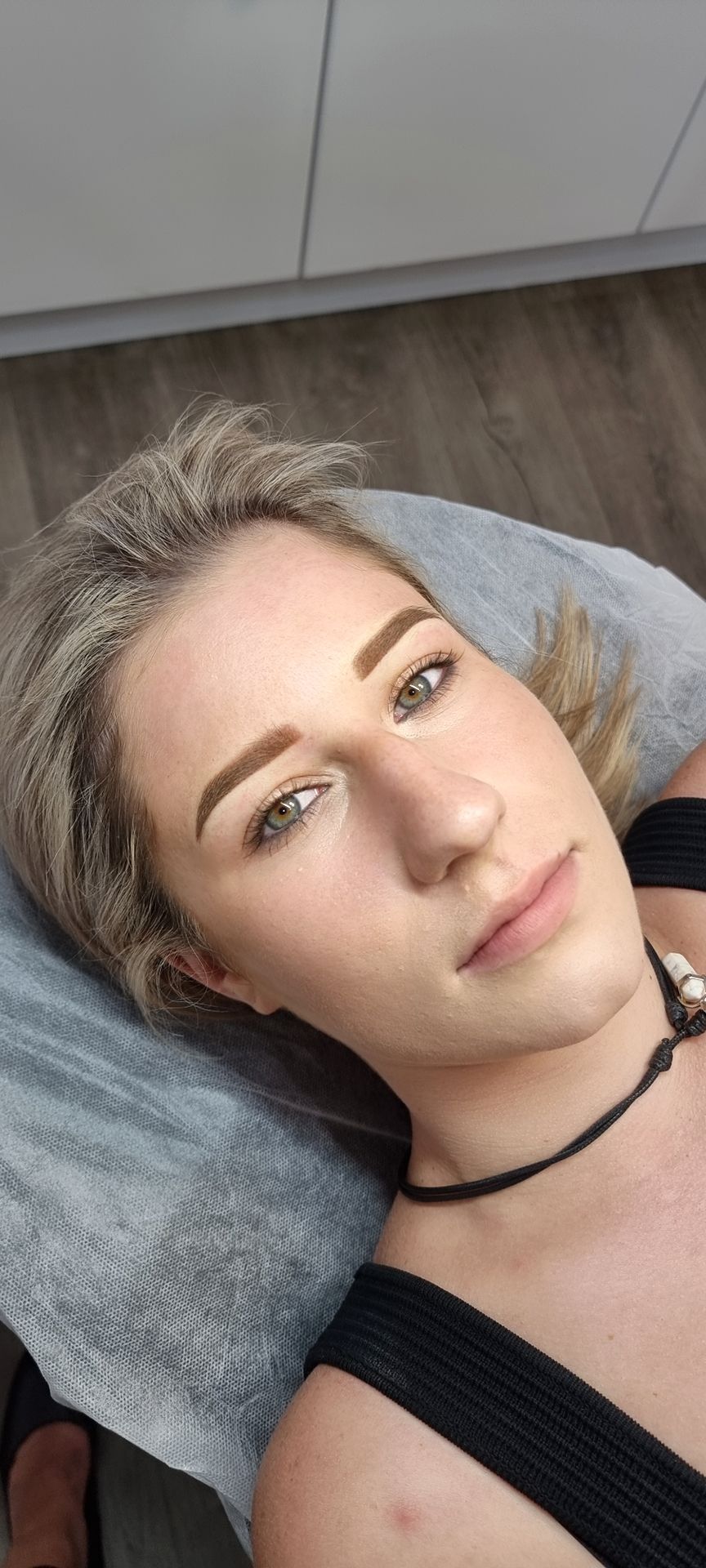 Close-up of a blonde woman's face showing freshly done, symmetrical powder brows.