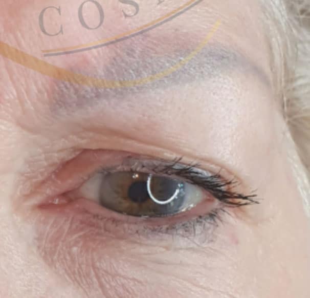 A close-up of an older person's right eye, showing a brown iris, dark eyelashes, and visible wrinkles around the eye.