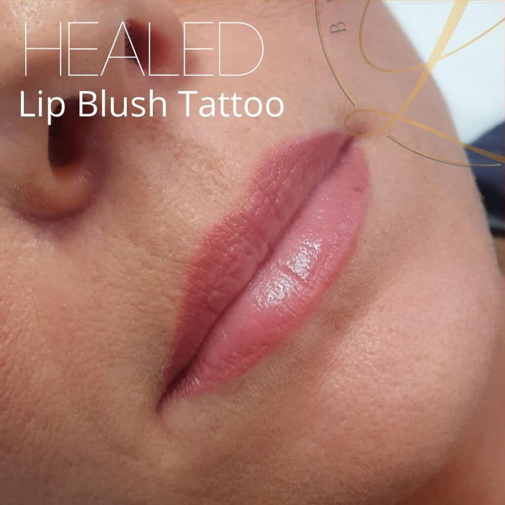 Close-up of a person's mouth showing a healed lip blush tattoo, with lips colored in a soft pink.