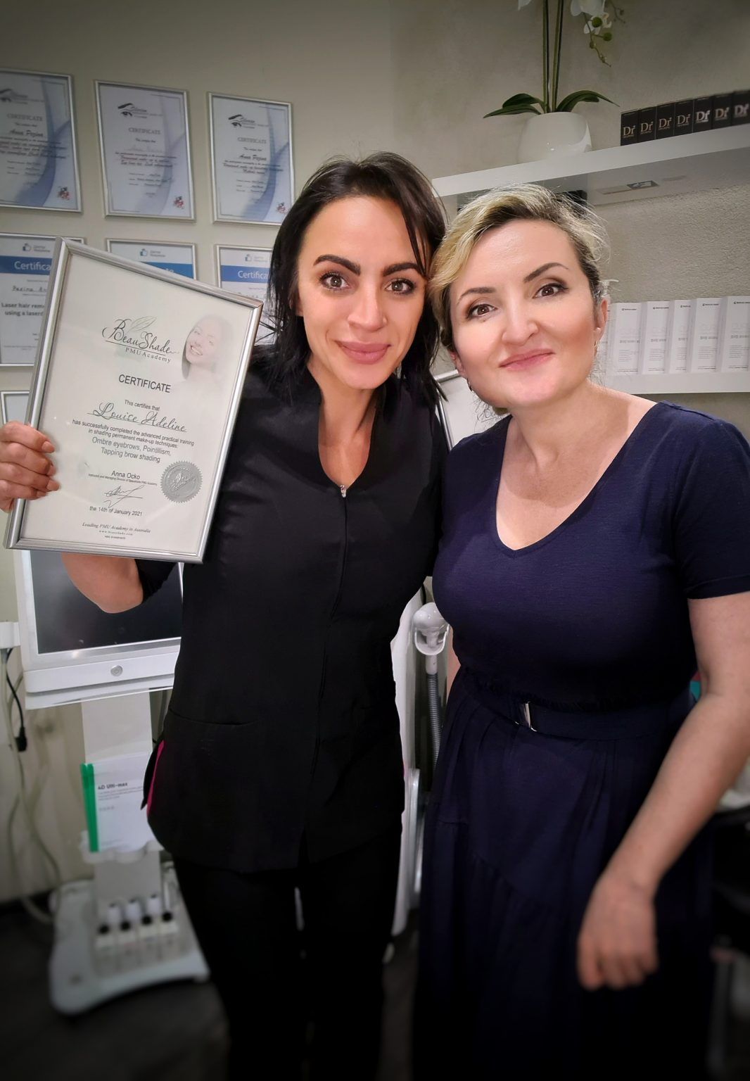 Two smiling women, one holding a Beau Shade PMU Academy certificate for Louise Adeline's advanced practical training.